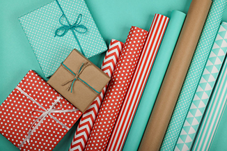 Close up packing and wrapping gifts with red, blue and brown paper, table top view, flat lay